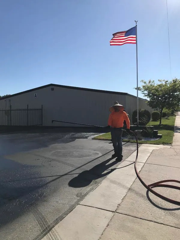 Sealcoating crew applying a fresh coat on a commercial lot