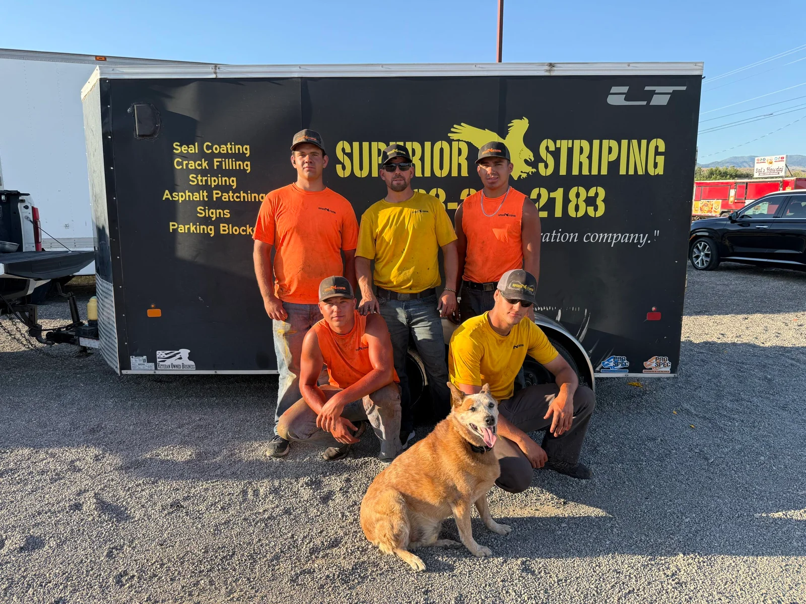 Superior Striping crew posing in front of their service trailer with their dog
