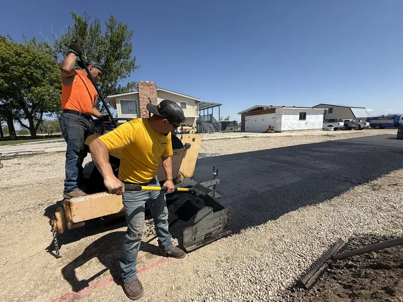 Paving Crew Spreading Hot Mix Asphalt On Gravel Road