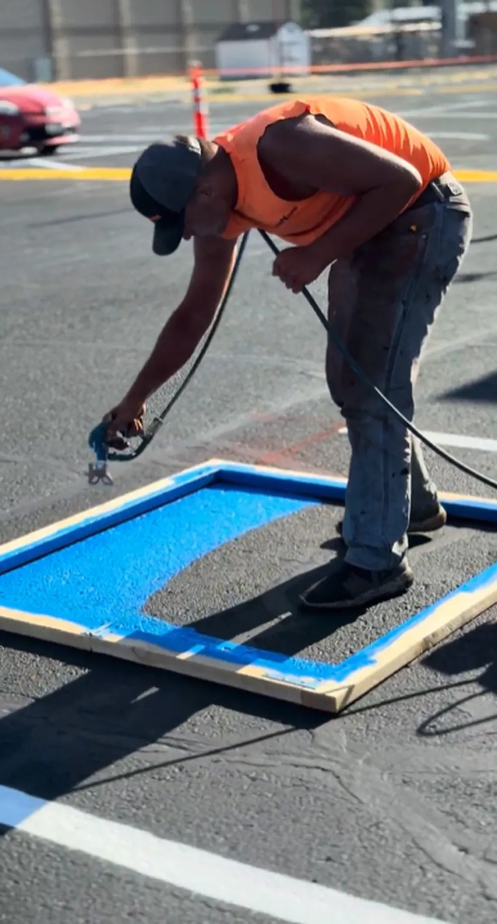 Superior Striping technician completing blue ADA handicap wheelchair symbol stencil on a sealcoated parking lot in Boise, Idaho