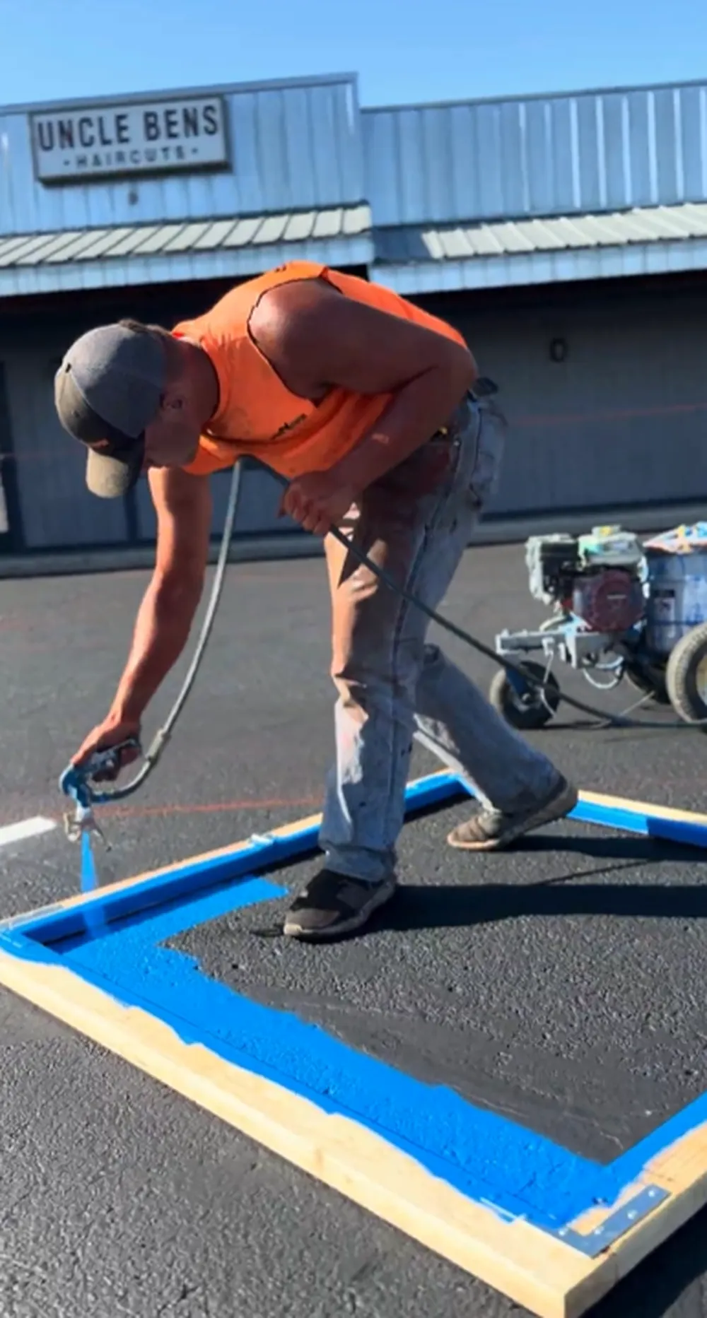 Superior Striping technician spraying blue paint inside an ADA handicap stencil frame on a freshly sealcoated parking lot in Boise, Idaho