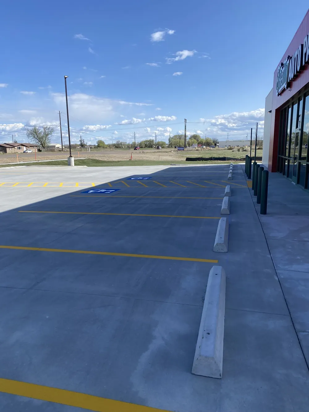Professional ADA handicap parking stencils, yellow line striping, concrete parking blocks, and safety bollards installed for a commercial storefront by Superior Striping in Treasure Valley.