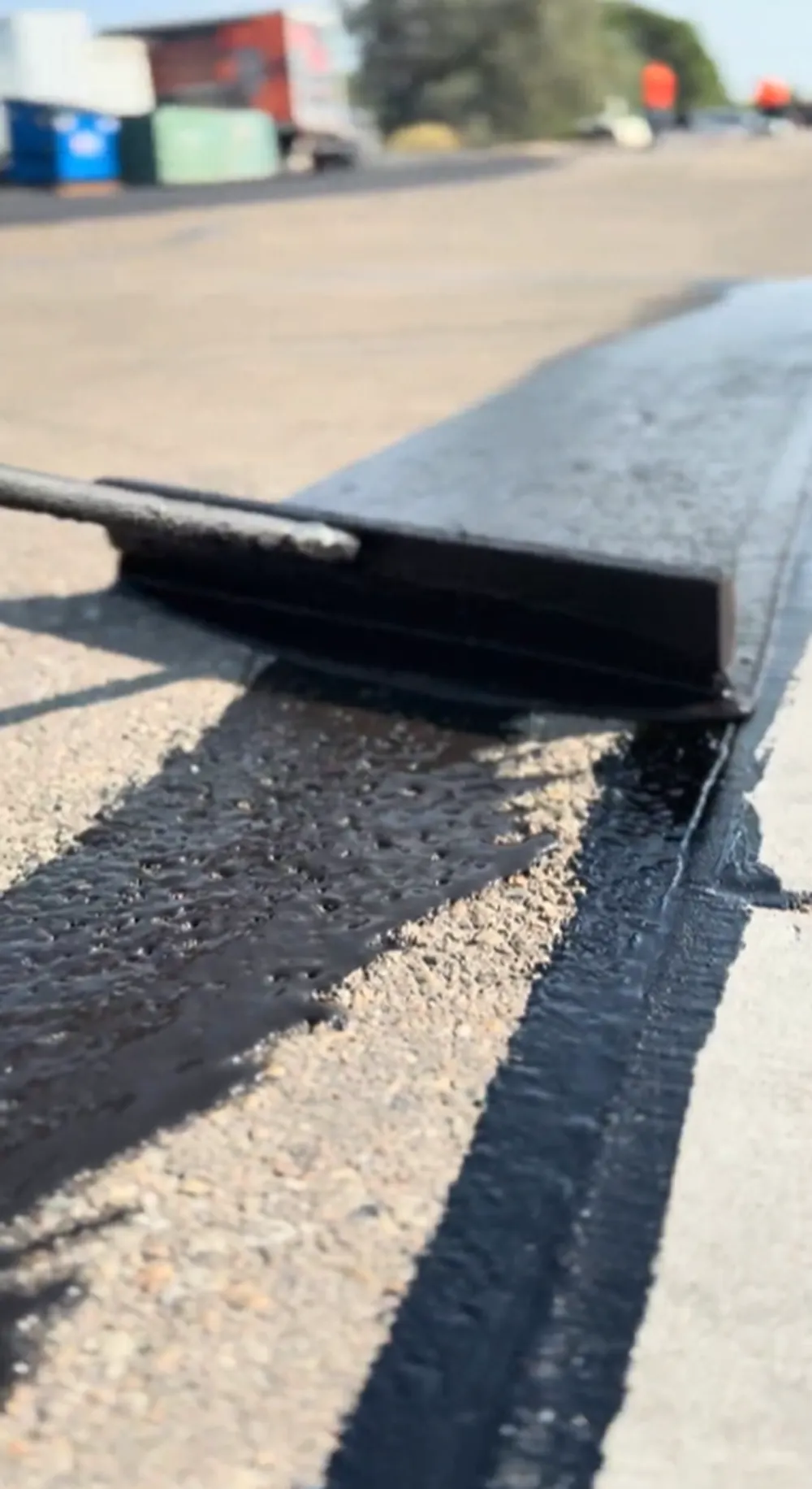 Sealcoating machine applying fresh black asphalt sealer on a commercial parking lot in Nampa, Idaho