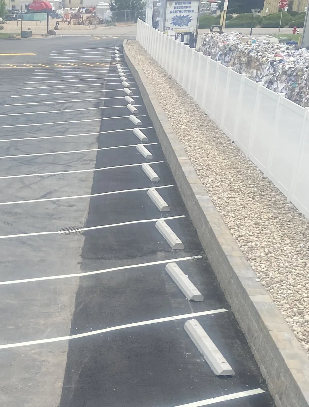 Newly installed concrete parking blocks and fresh white line striping in a Treasure Valley commercial parking lot by Superior Striping.