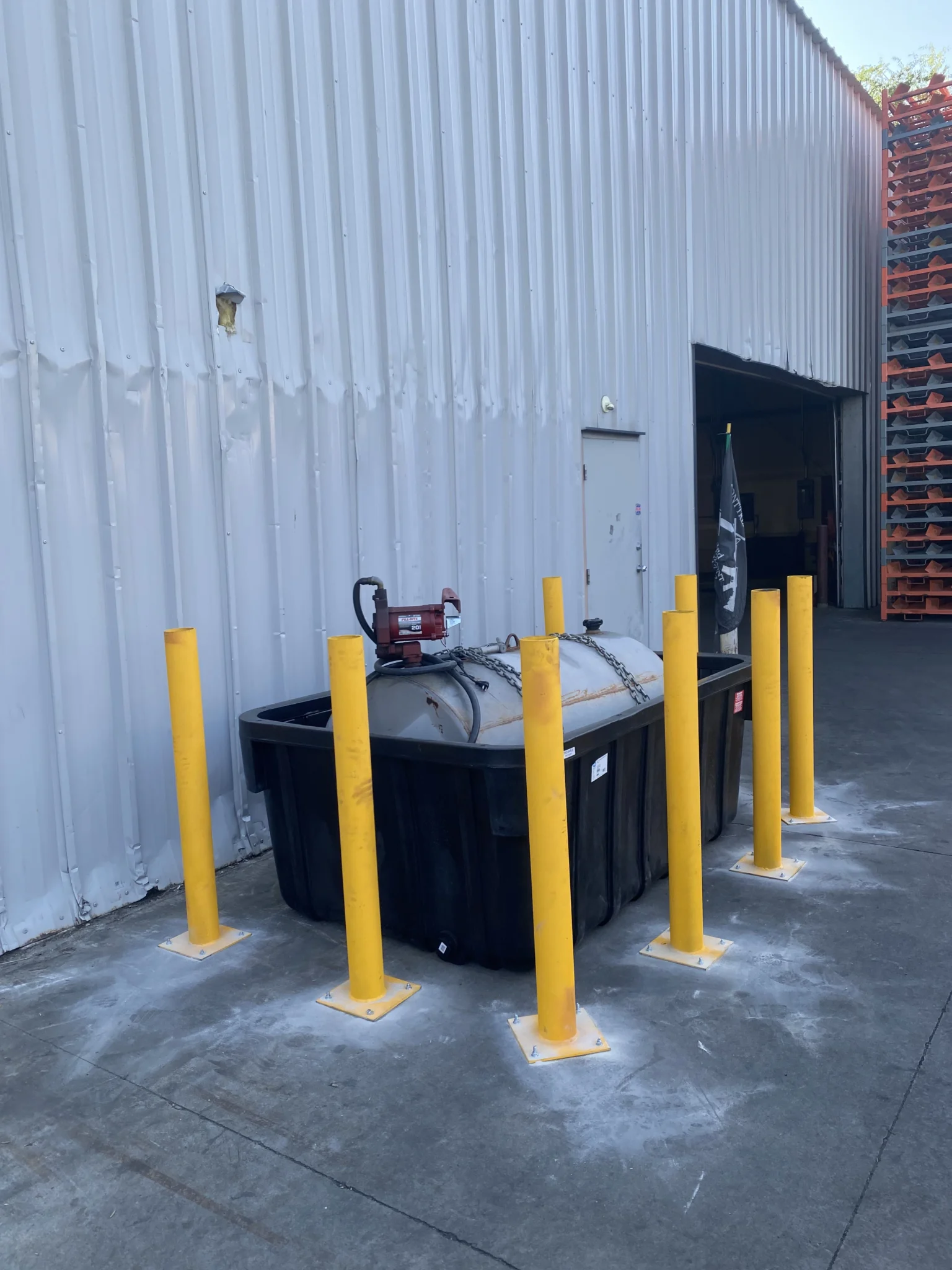 Surface-mounted yellow safety bollards installed around a fuel tank and secondary containment bin to provide industrial asset protection in Treasure Valley by Superior Striping.