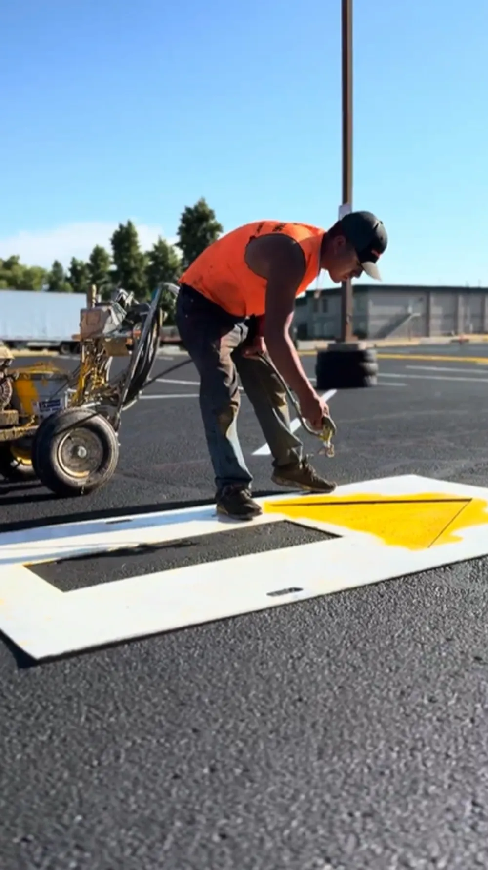 Superior Striping technician placing a stencil to paint a yellow directional arrow on a freshly sealcoated parking lot in Boise, Idaho