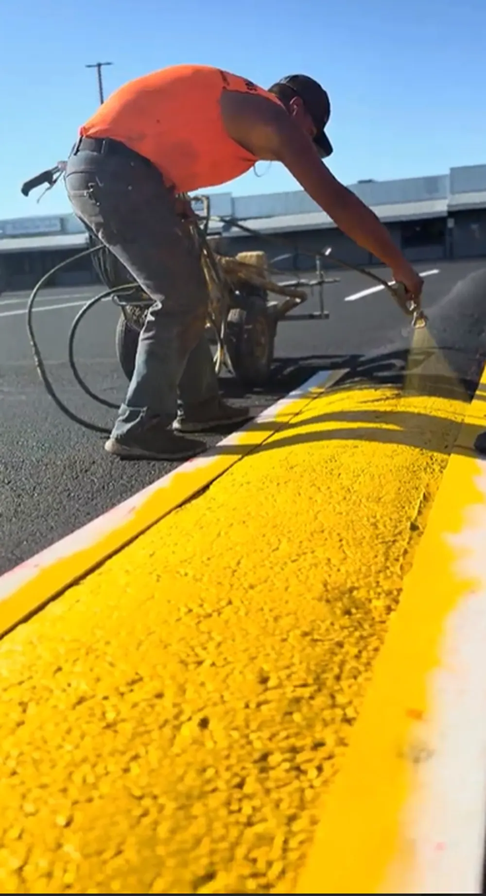 Superior Striping technician spray painting bright yellow speed bump with professional equipment in Boise, Idaho