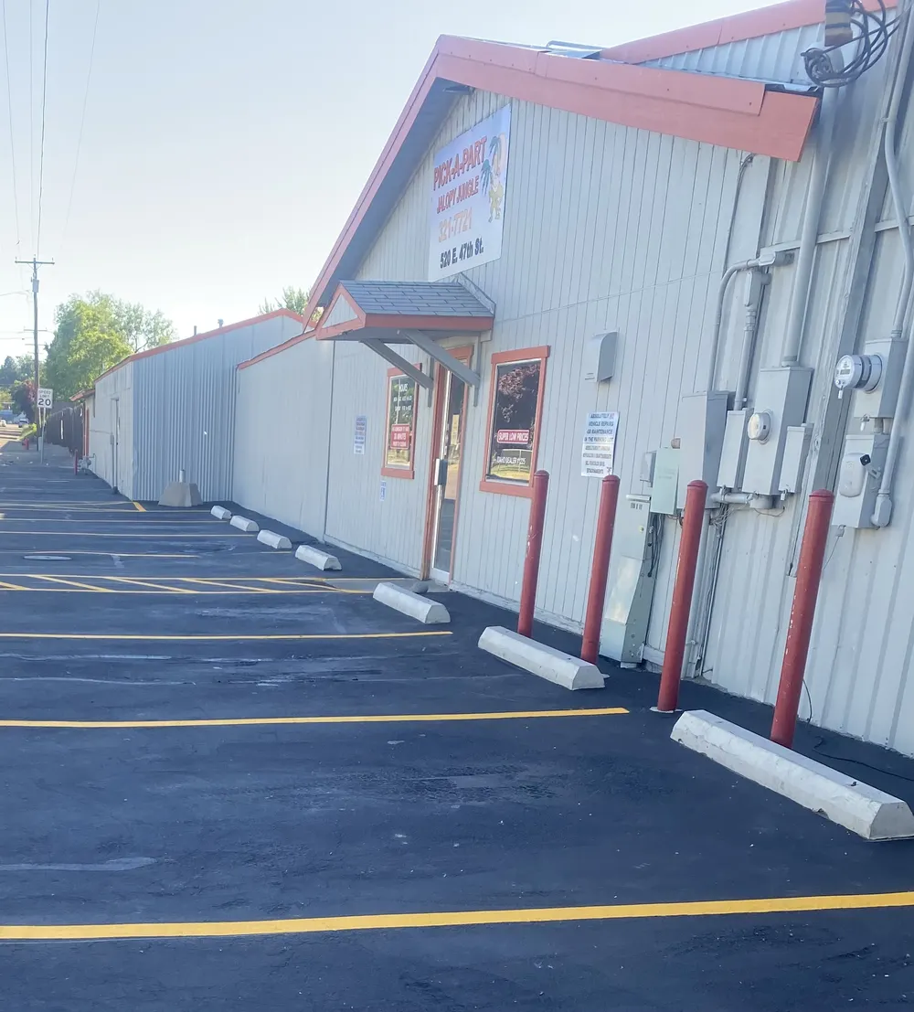 Commercial parking lot maintenance featuring red safety bollards, concrete parking blocks, and fresh yellow line striping installed by Superior Striping in Treasure Valley.