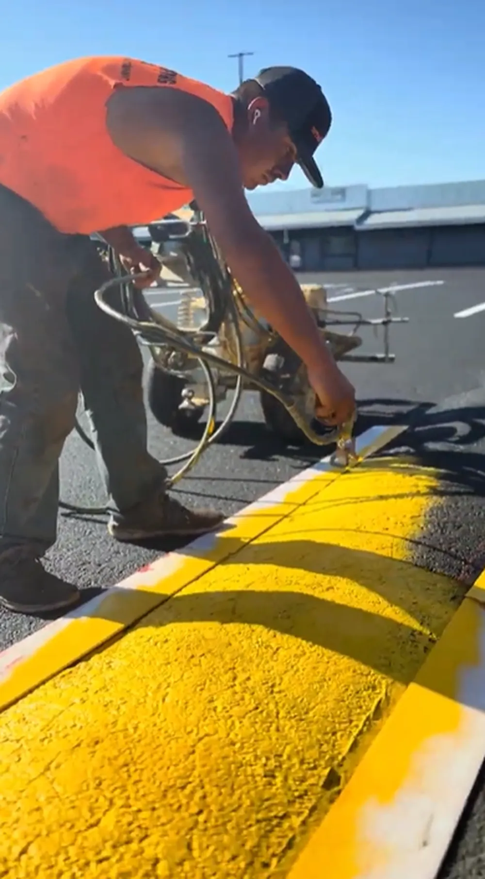 Superior Striping technician applying yellow paint to a speed bump with a spray gun in Boise, Idaho