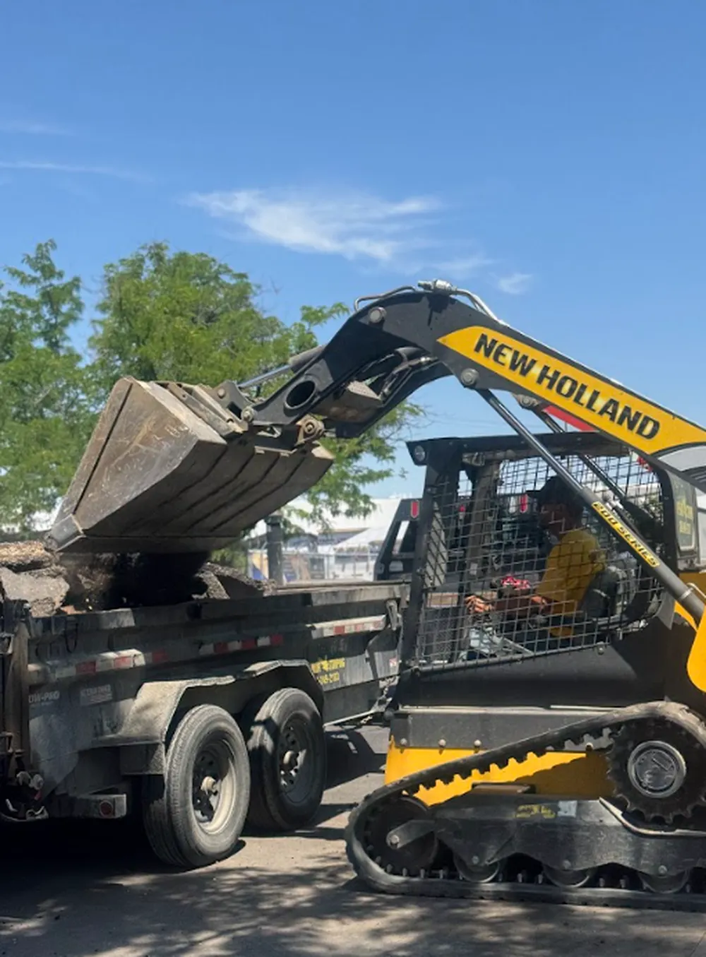 Superior Striping New Holland Skid Steer Loading Asphalt into Dump Trailer in Boise, Idaho
