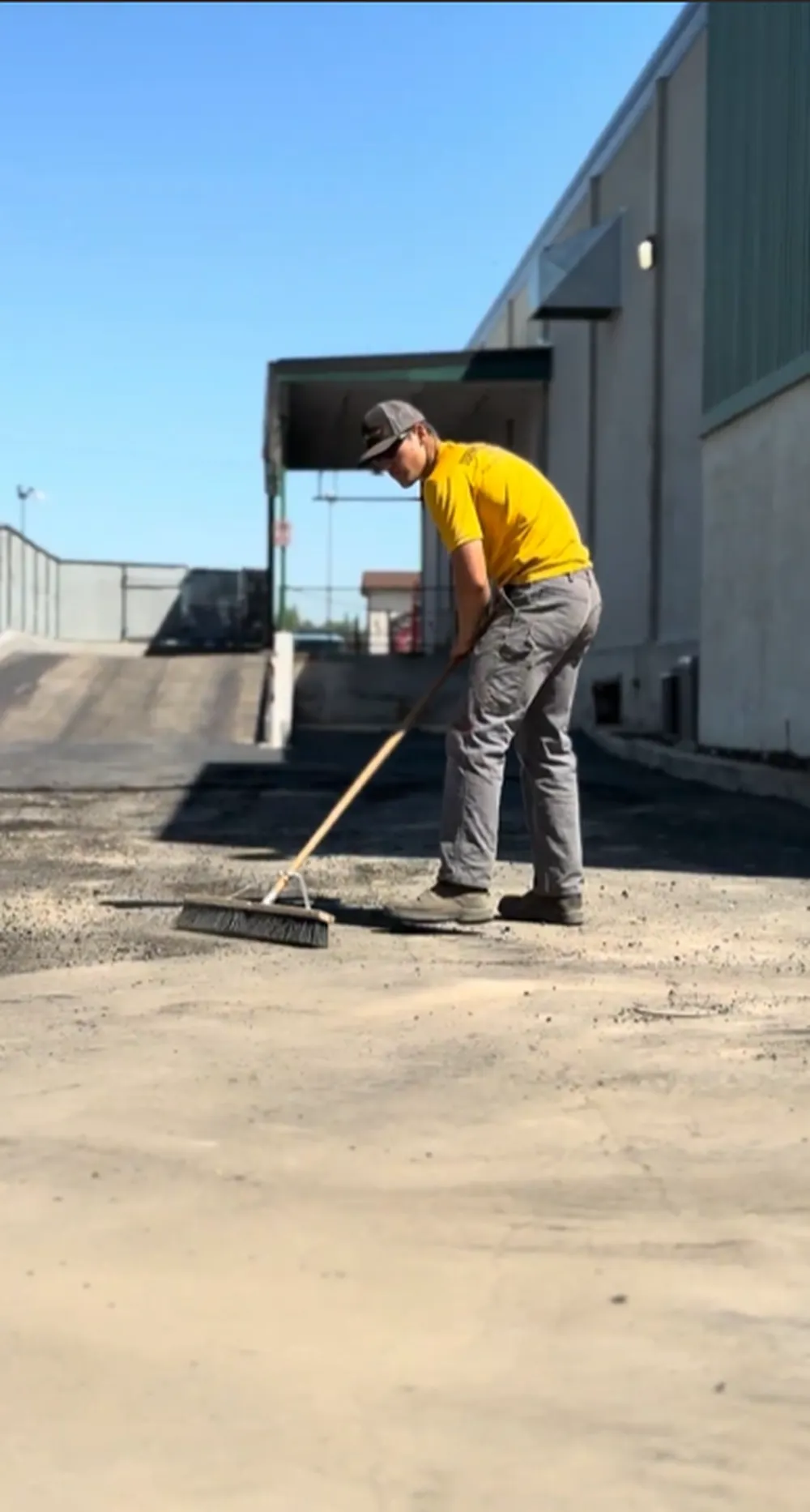Superior Striping Worker Sweeping Gravel Base Clean Next to Commercial Building Before Asphalt Paving in Boise, Idaho