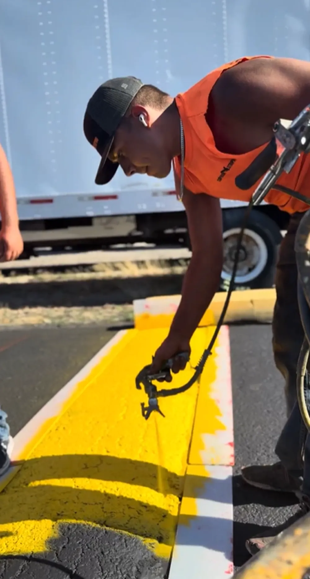 Superior Striping technician spray painting yellow curb with professional striping equipment in Boise, Idaho