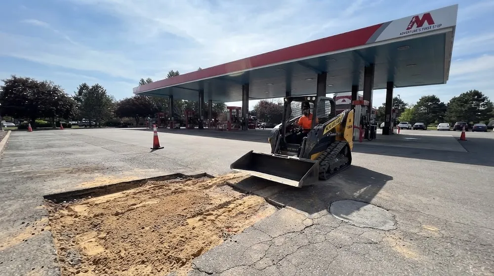 Skid steer loader clearing out a section of damaged pavement for asphalt patching at a gas station in Boise Idaho