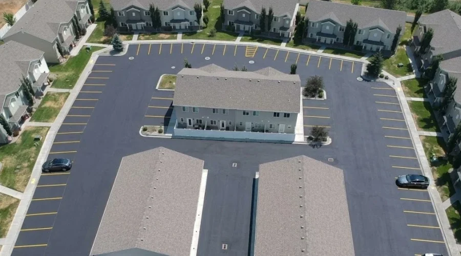 Aerial view of an apartment complex parking lot in Twin Falls, Idaho, featuring fresh black sealcoating and bright yellow parking line striping, professionally completed by Superior Striping.