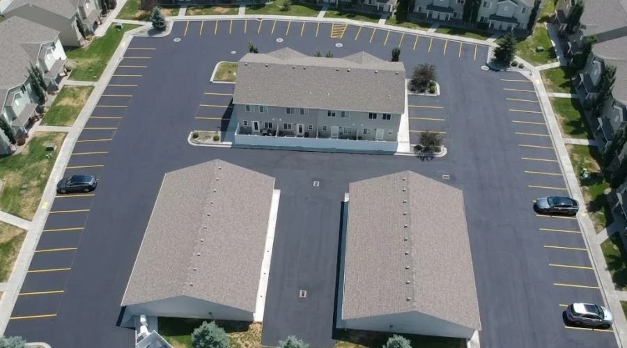 Aerial view of an apartment complex parking lot in Twin Falls, Idaho, featuring fresh black sealcoating and bright yellow parking line striping, professionally completed by Superior Striping.